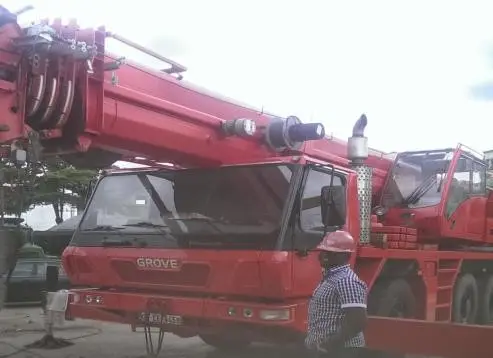 Red mobile crane with operator alongside