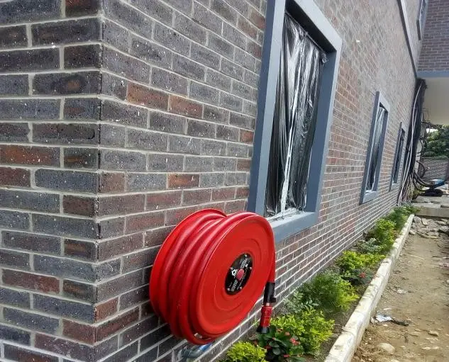 Red fire hose reel mounted on a brick building wall